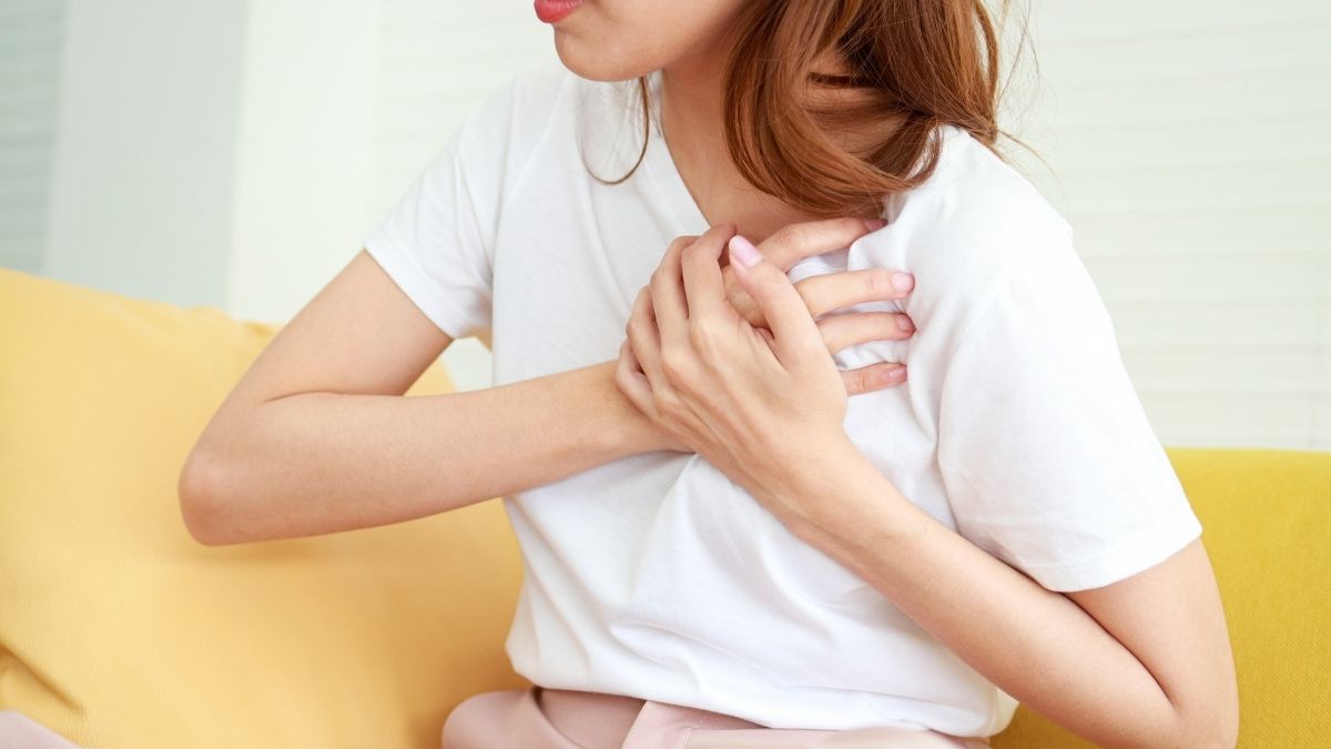 A photo of a woman holding her chest area like she is in pain